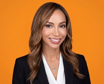 HeadshotPro’s published result: a woman in a dark blazer against an orange background