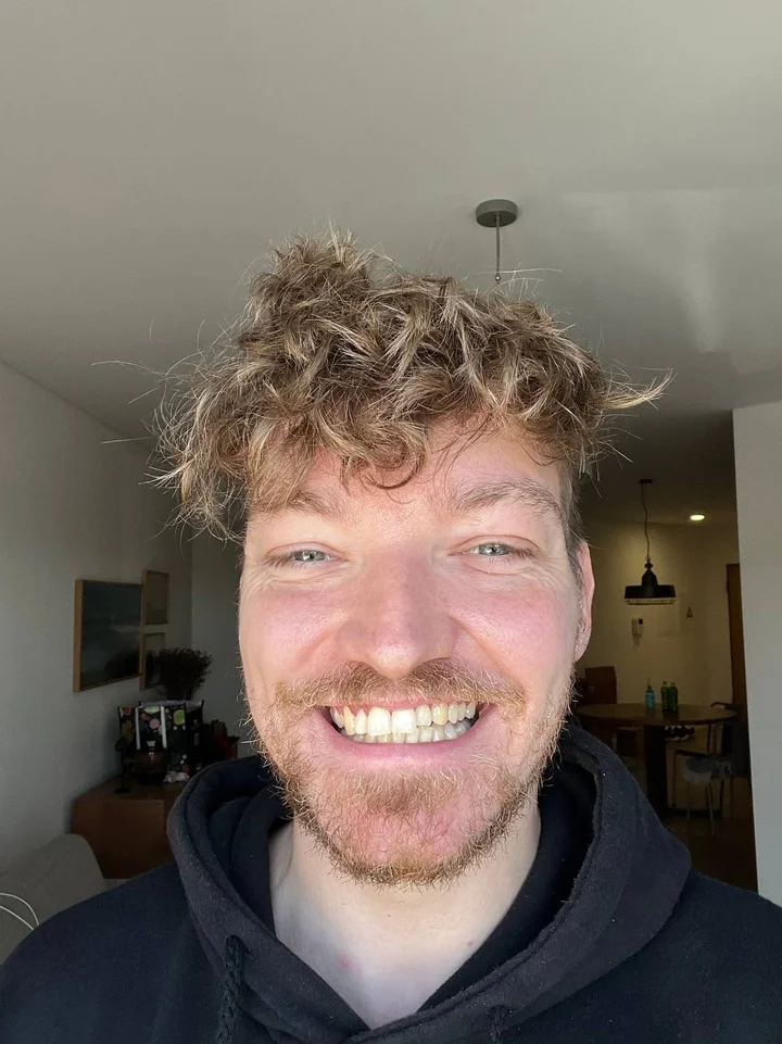 Photo AI’s published reference: an indoor close-up selfie of a man in a dark hoodie